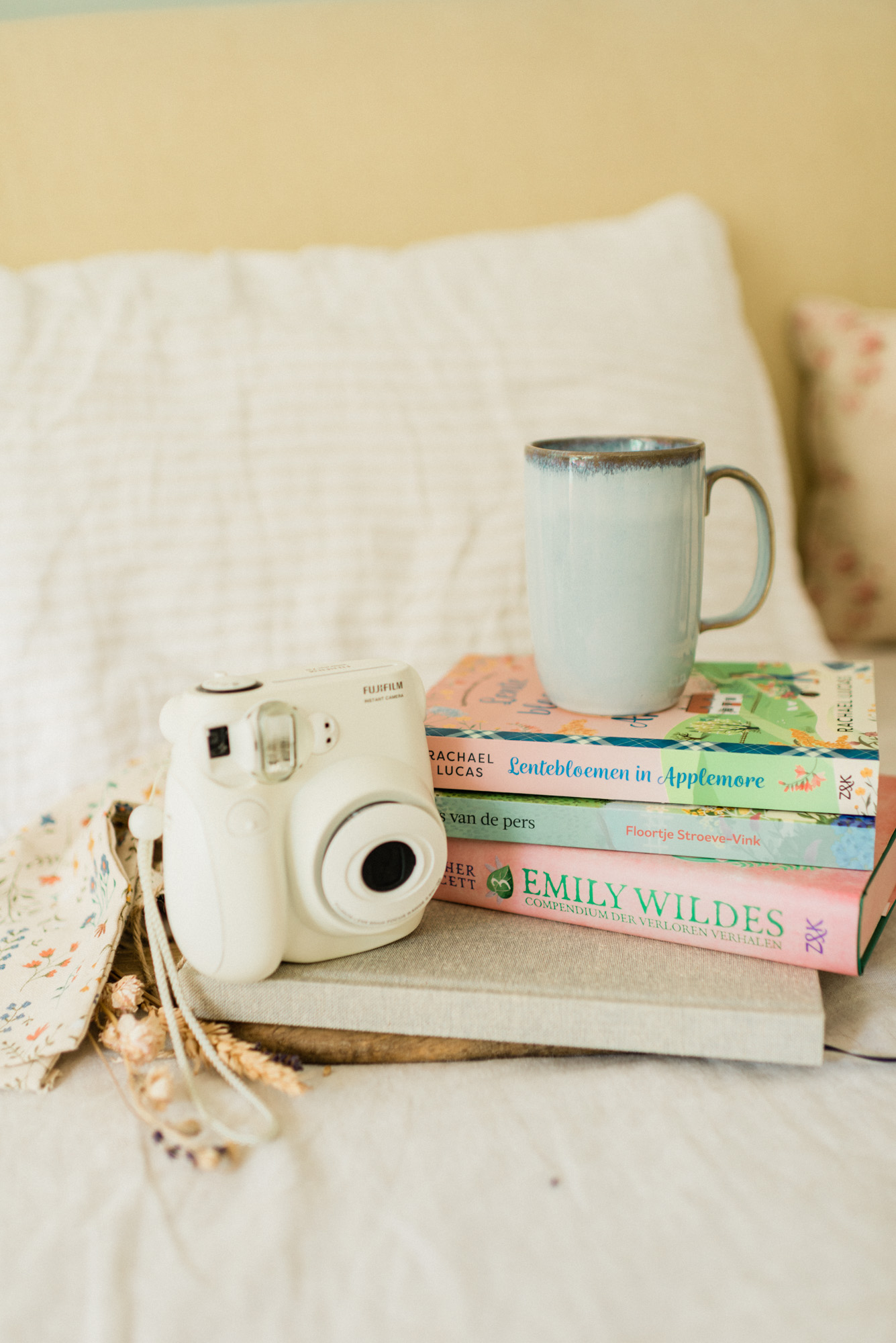 Boeken, een mok en een Instax-camera in een sfeervolle setting — een beeld dat de onderdompeling van de lezer (reader immersion) oproept.