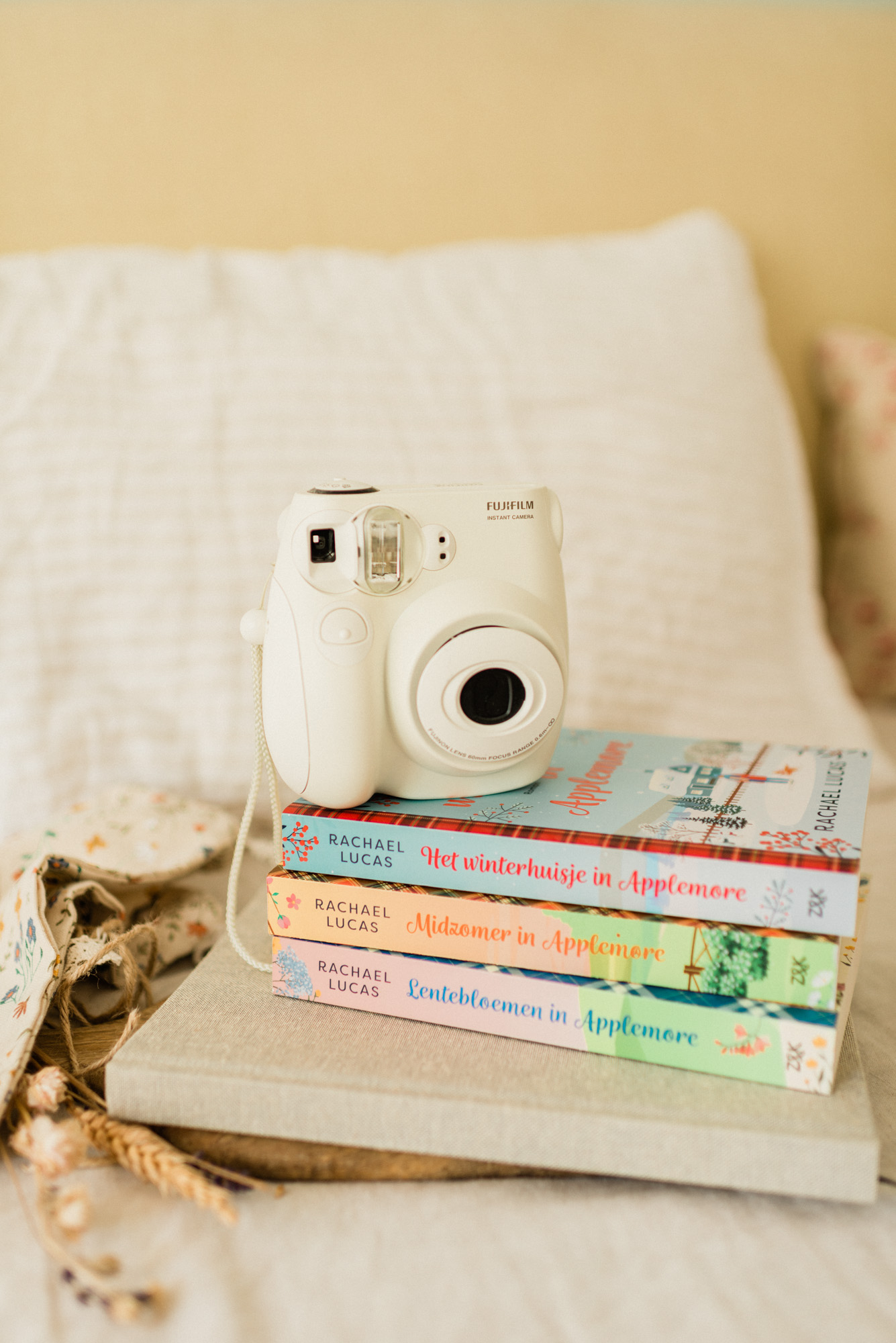 Drie boeken op een stapel met een polaroidcamera in pastelkleuren, passend bij een artikel over plotproblemen bij fictieschrijvers
