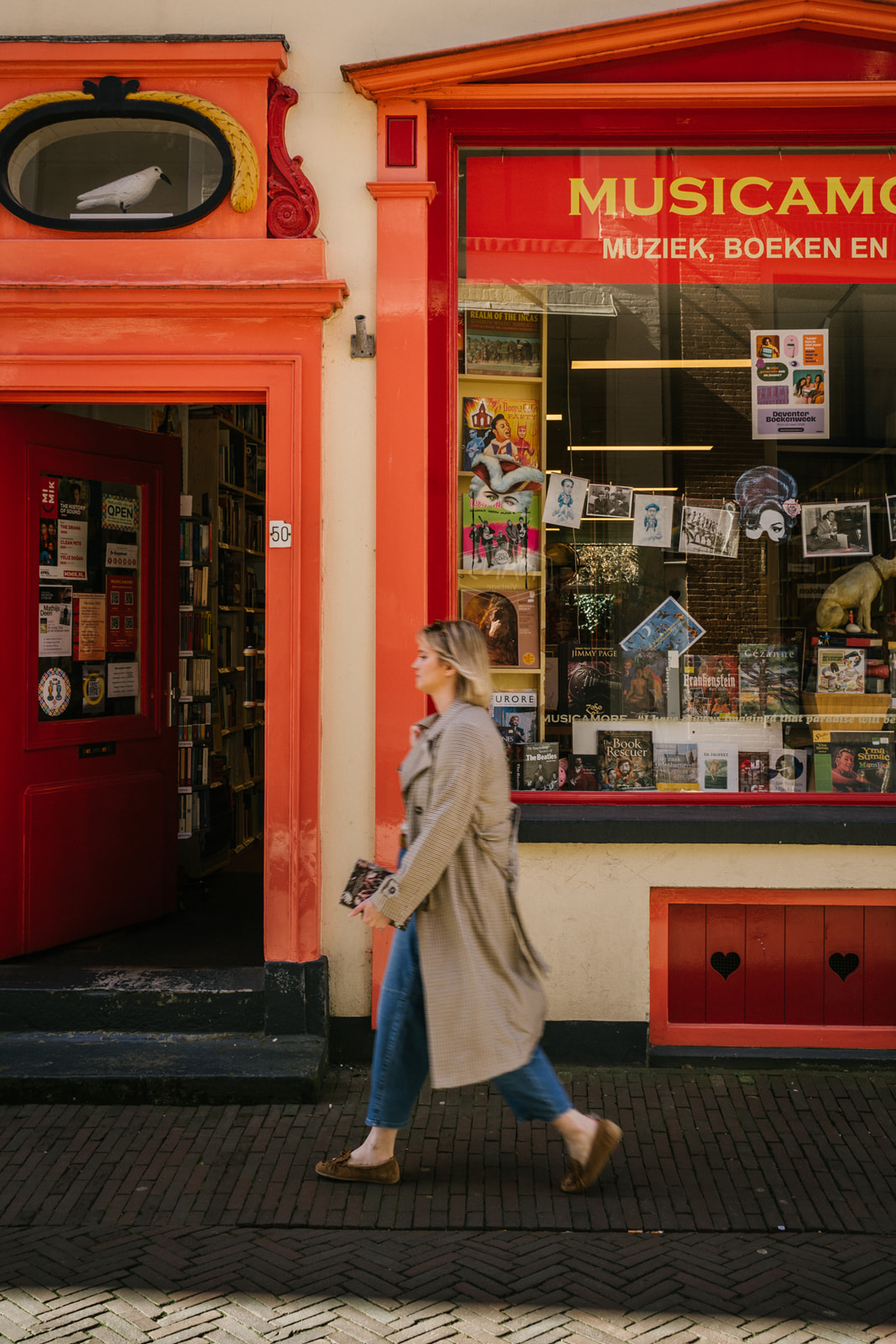 Rosanne van Cruijningen, redacteur en schrijfcoach, loopt langs een kleurrijke boeken- en muziekwinkel in Deventer